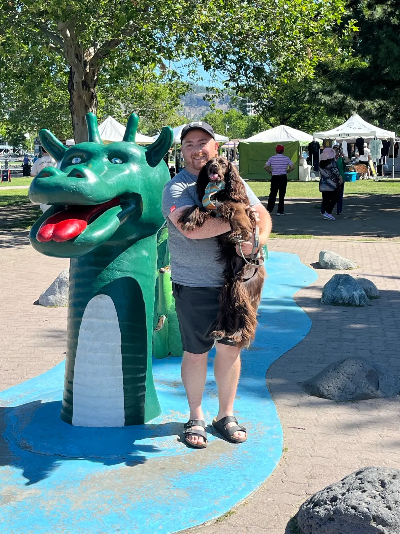 Tilly et Shaun à côté de la figure verte de l’Ogopogo sur le bord de l’eau de Kelowna