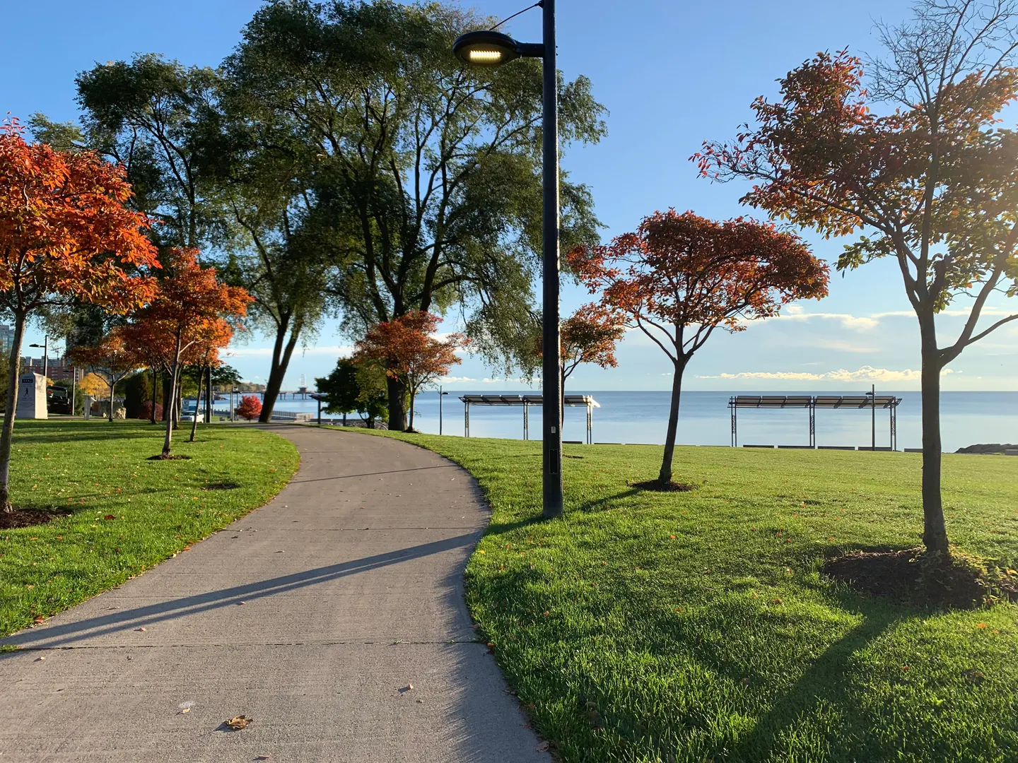 Sentier pavé serpentant dans le Spencer Smith Park avec des arbres orange en automne et le lac Ontario au loin