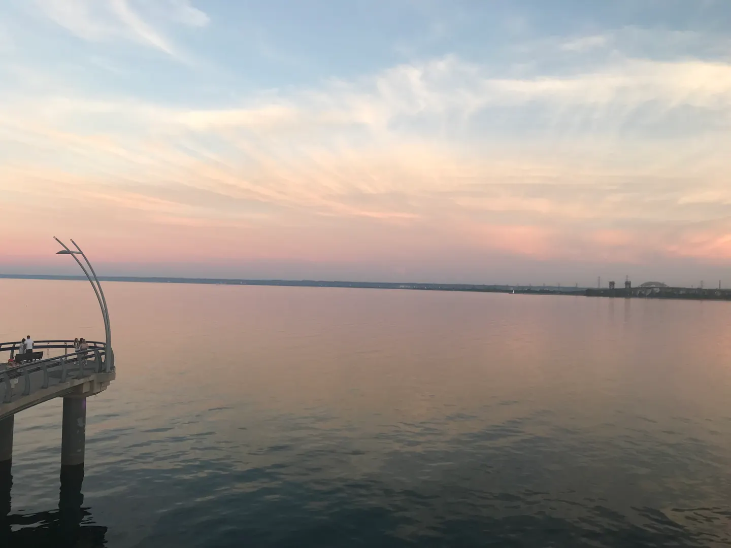 Coucher de soleil sur la jetée du Spencer Smith Park avec un ciel rose et pêche au-dessus de l’eau calme
